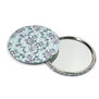Two round pocket mirrors. One is arranged to show the mirrored side, while the other one displays the floral pattern on pale blue on the other side.